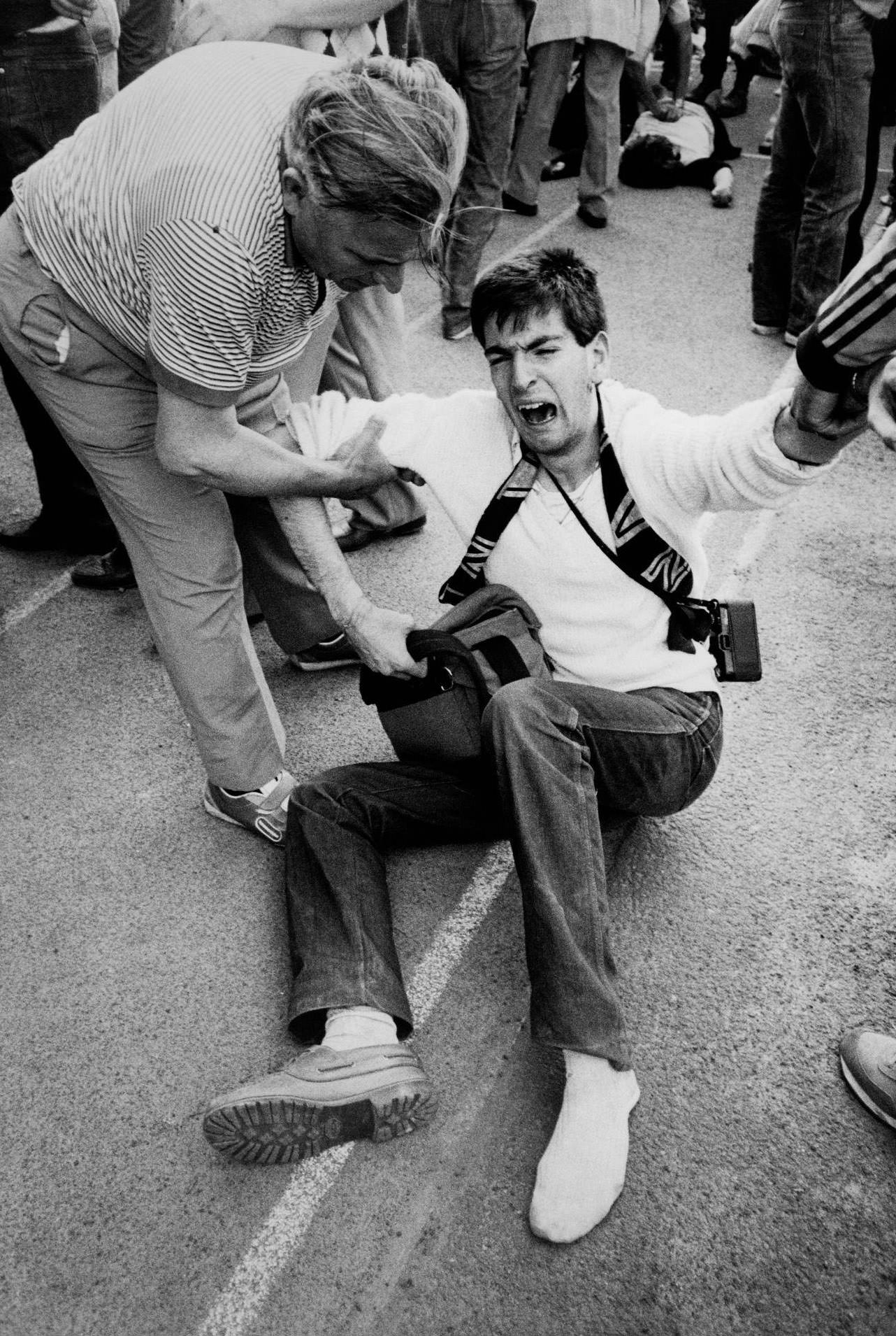 Distraught man sits on the ground after Juventus fans crushed at Heysel Stadium, European Cup Final, 1985.