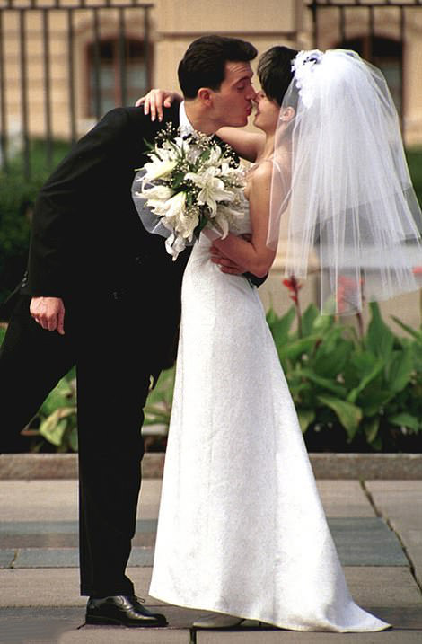 Wedding Moment: A groom leans in for a kiss, making his bride laugh