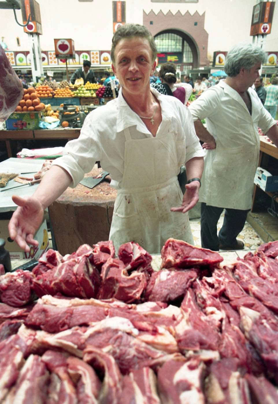 Market Freshness: Worker displays fresh cuts as customers browse produce