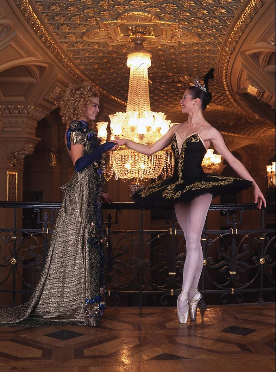 Ballet Elegance: Dancer in black and gold dress holds another's hand
