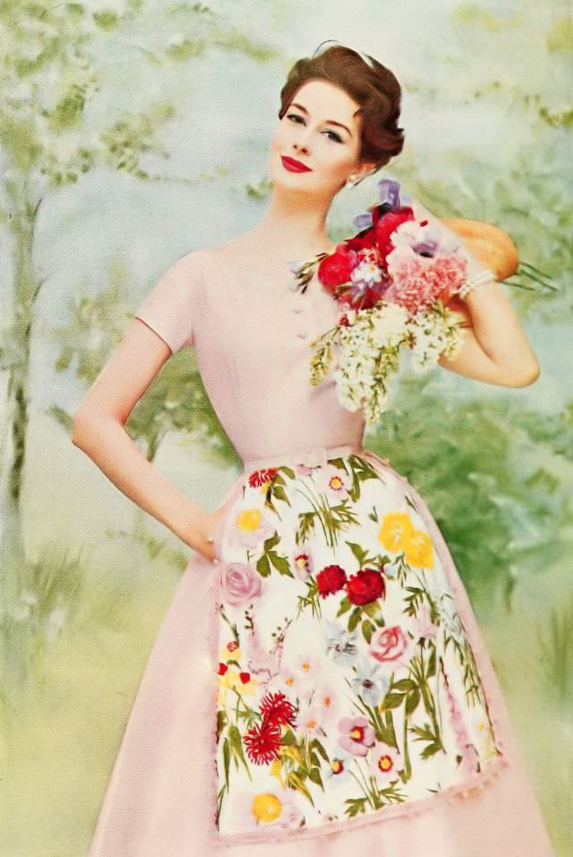Nancy Berg in a pale pink dress adorned with a flowered chintz apron sparkled with sequins, 1957.