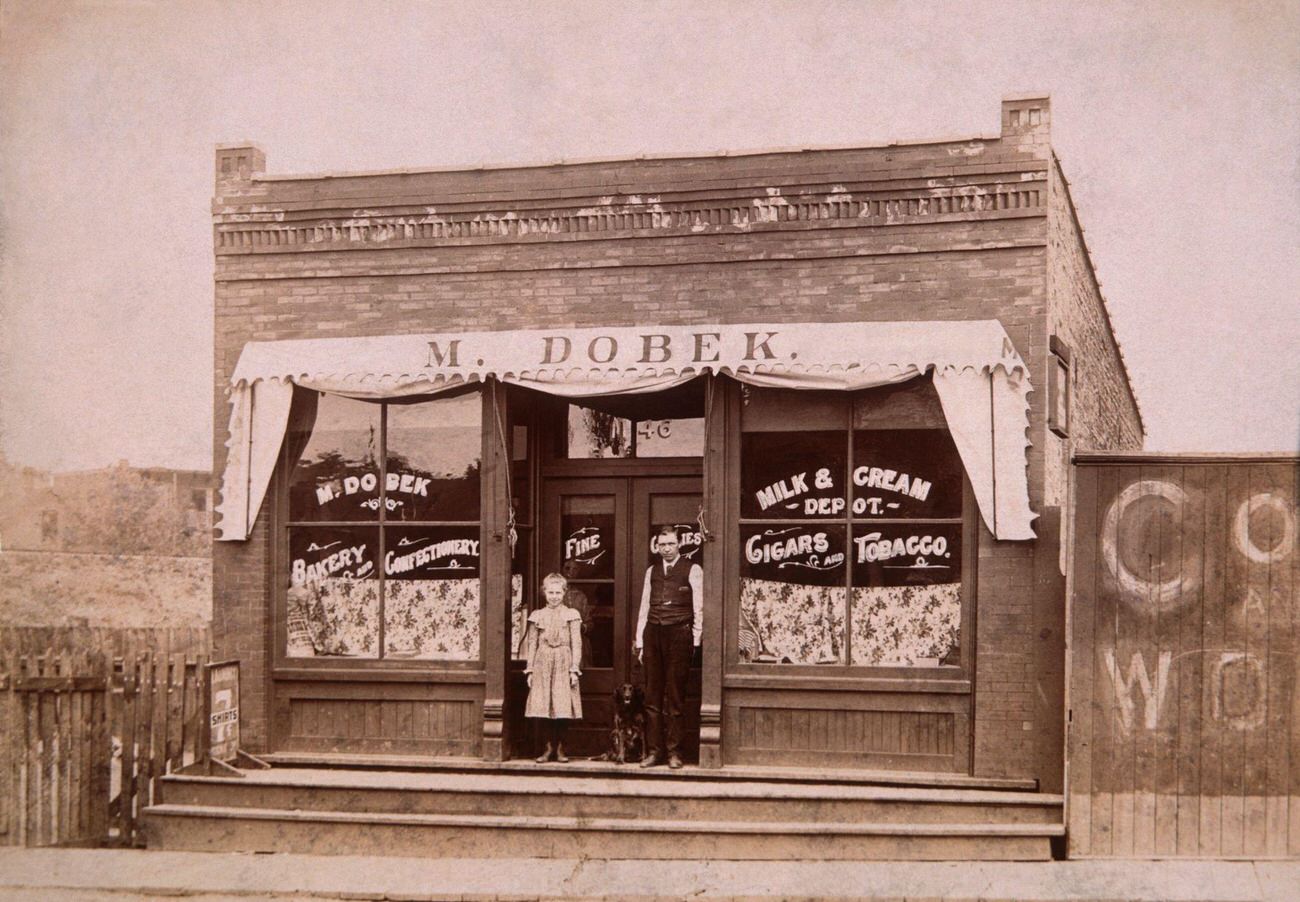 Girl, Dog, and Man Outside Store, 1900