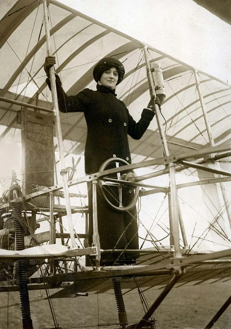 Baroness Elise Deroche posing on the wing of an airplane.