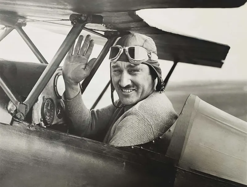 The early pilot Bert Acosta waving before take off in a tiny monoplane.