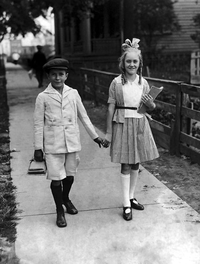 A young boy and girl on the way to school for the start of a new term in the 1920s