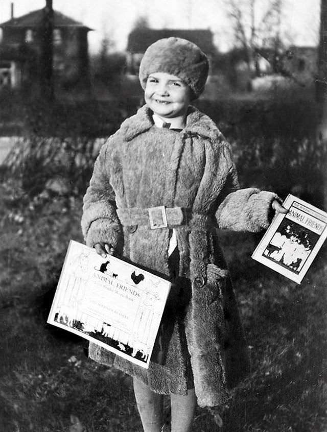 A 5-year-old girl shows off her books after her first day of kindergarten, circa 1929
