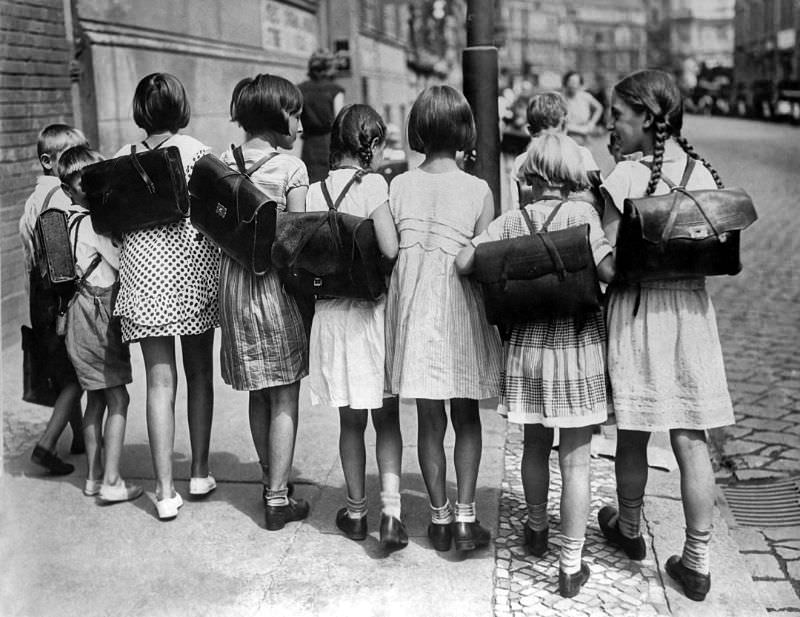 Children on their way home from school, with book bags strapped on their backs, after the first day of classes in Germany, circa 1930