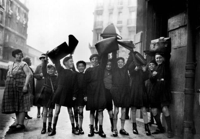 Students in France greet a photographer at the start of a new term by shaking their schoolbags in 1932