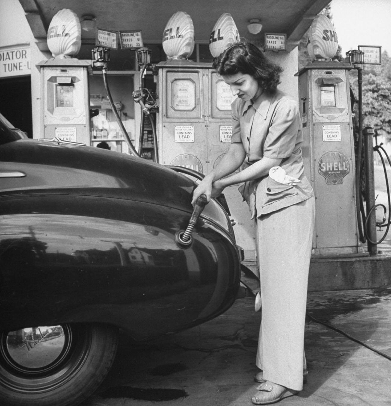 Woman replaces men in vital war industries, working at a gas station.