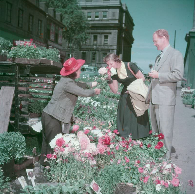 A woman smelling some flowers offered by a vendor at the Bonsecours market.