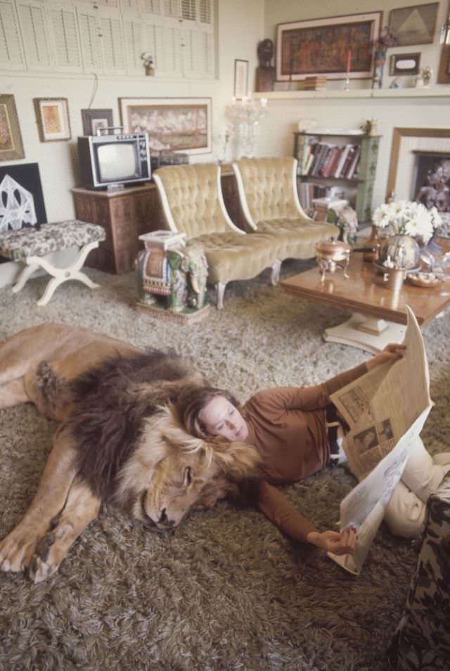 Tippi Hedren leans against her pet lion Neil while reading a newspaper, Sherman Oaks, 1971.