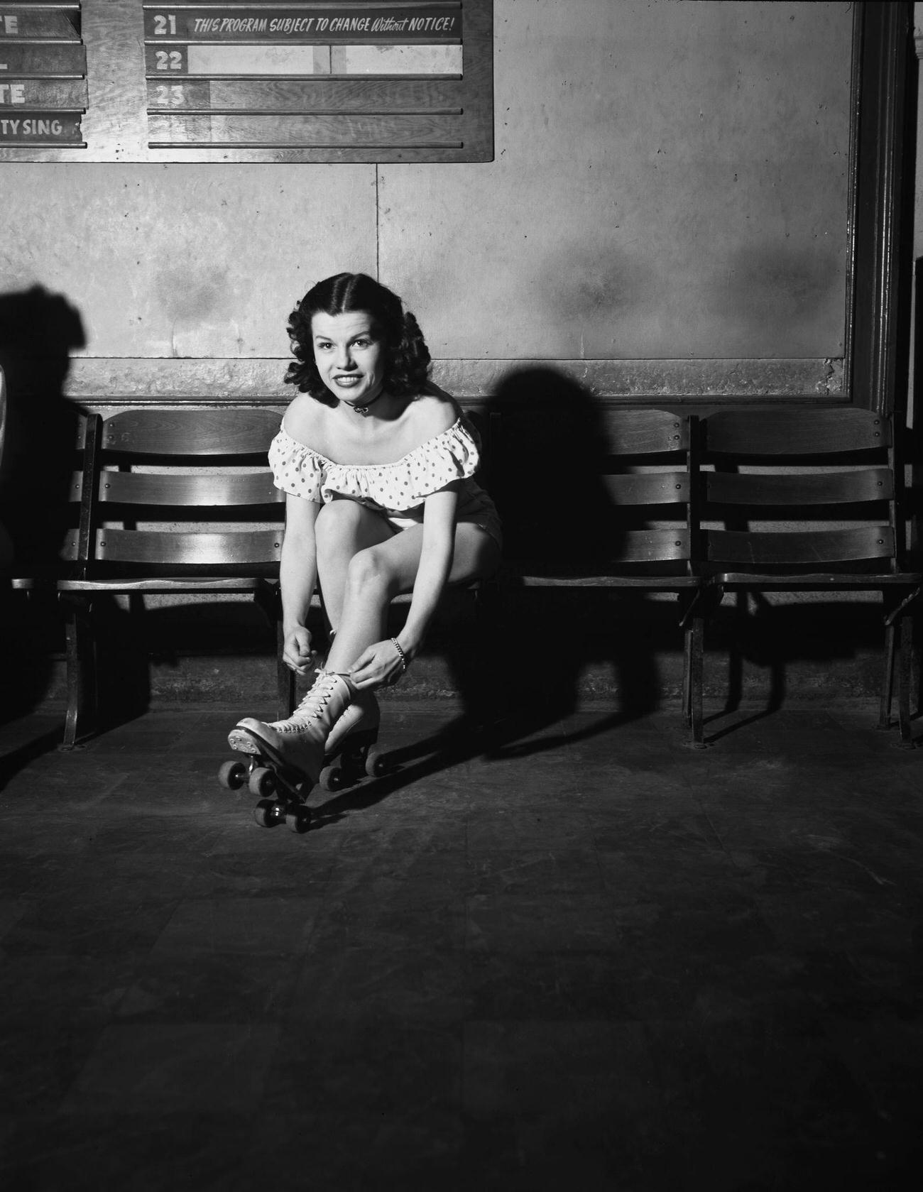 Young Woman Putting on Roller Skates at a Rink, USA, circa 1950