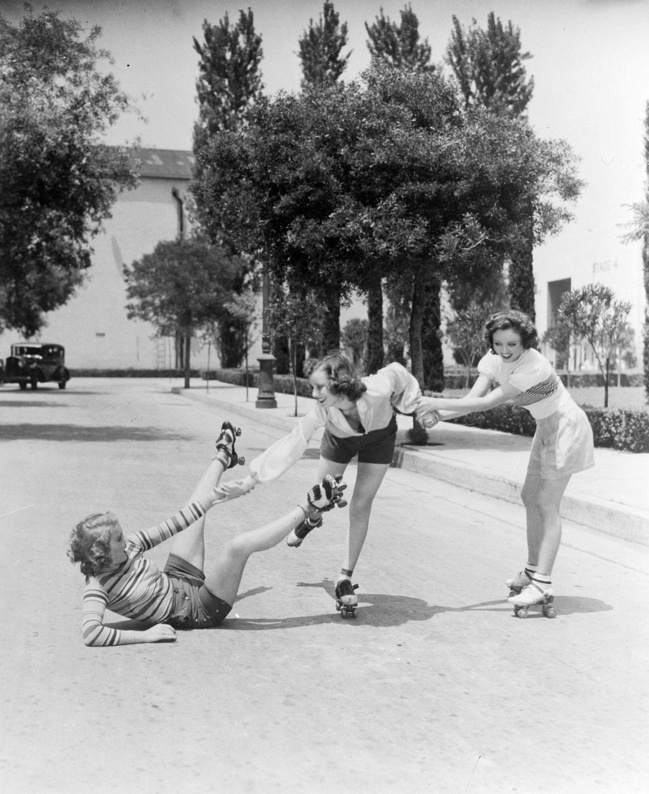 Three Girls Roller Skating, One Being Helped After a Fall, 1933.