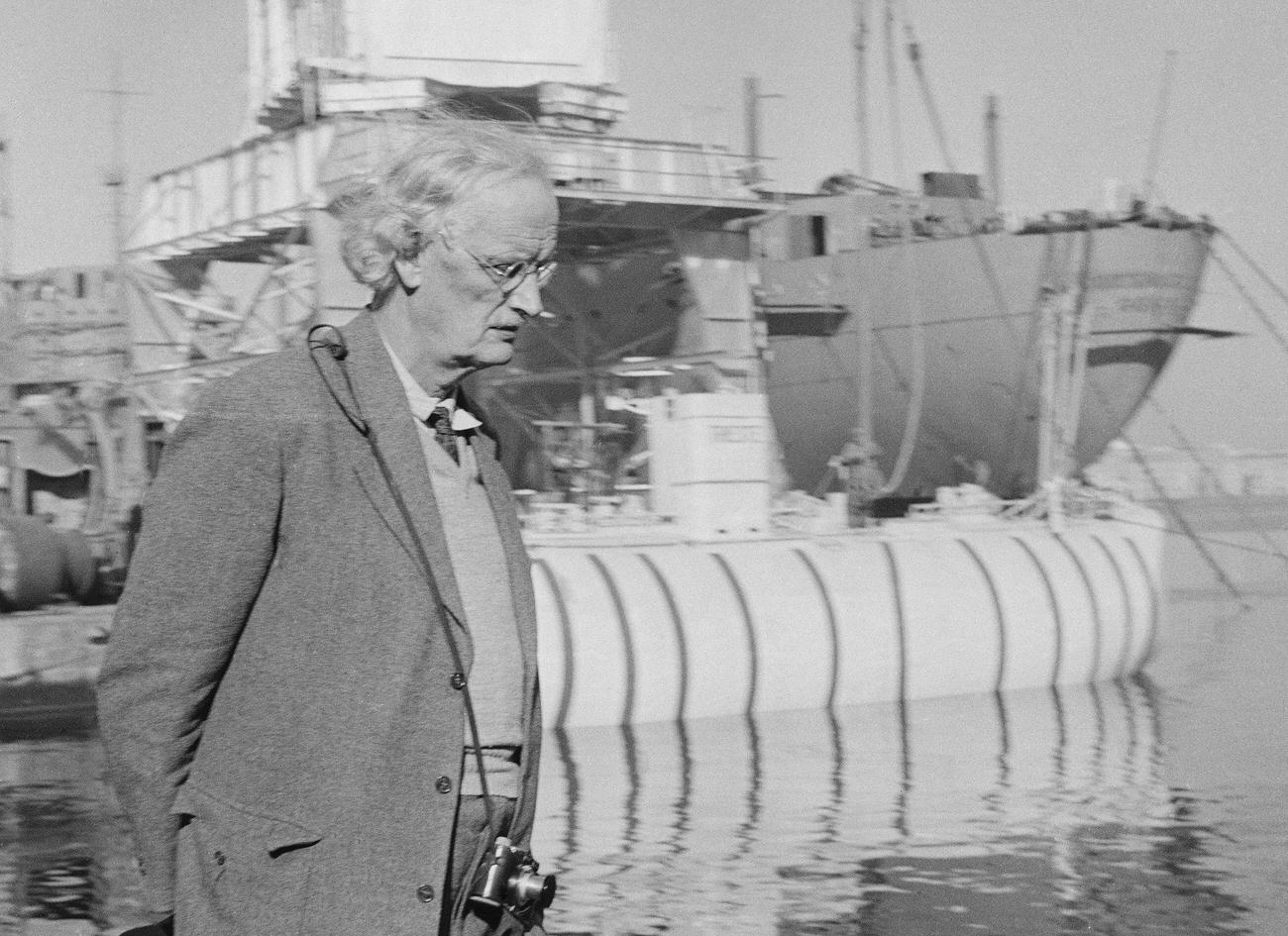 Auguste Piccard strolling along a Castellamare pier after bathysphere 'Trieste' test drive.