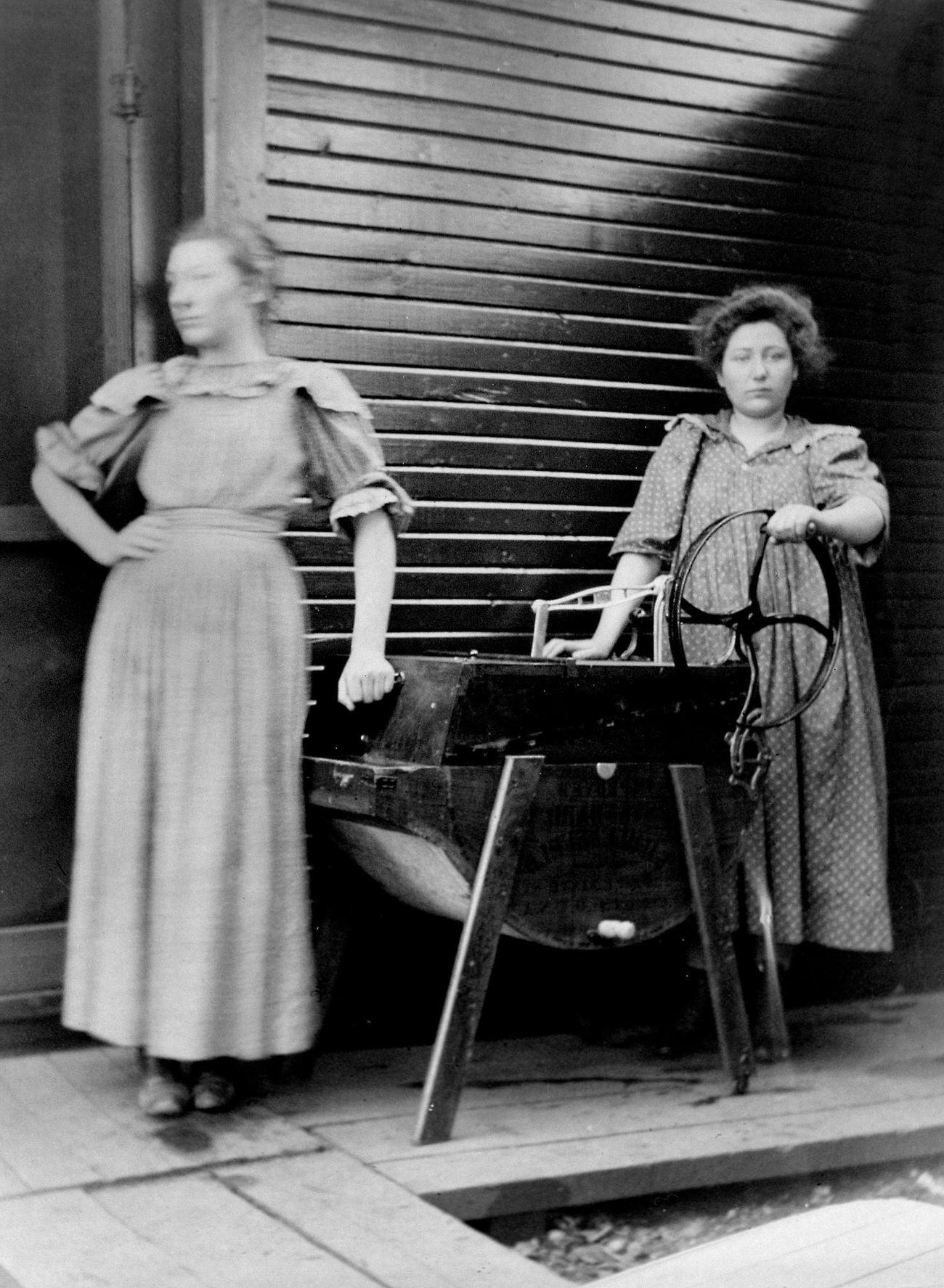 Two women posing with a modern washing machine, 1900.