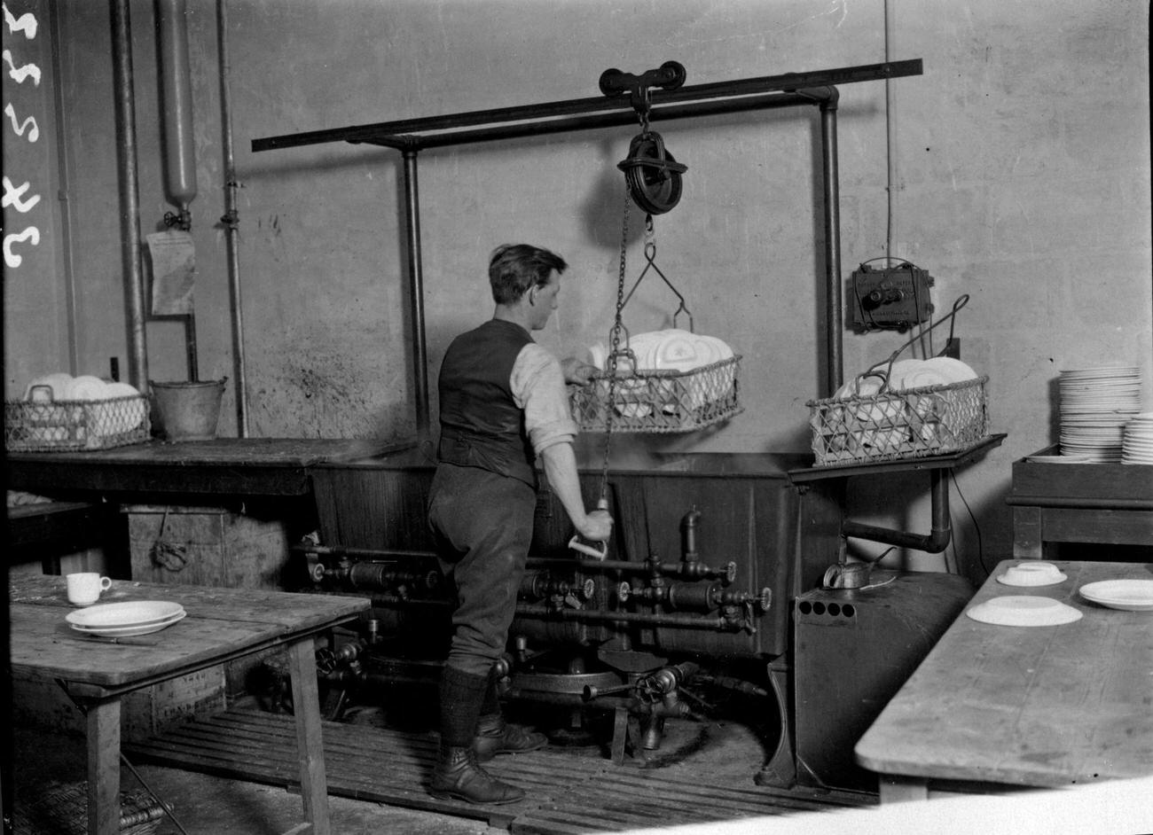 Man operating an electrical dishwashing gadget, 1922.
