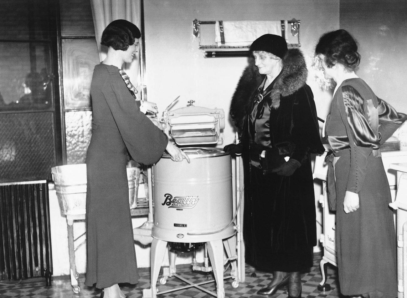 Lady Moir and Miss. Minoprio inspecting a combined washing machine and mangle.