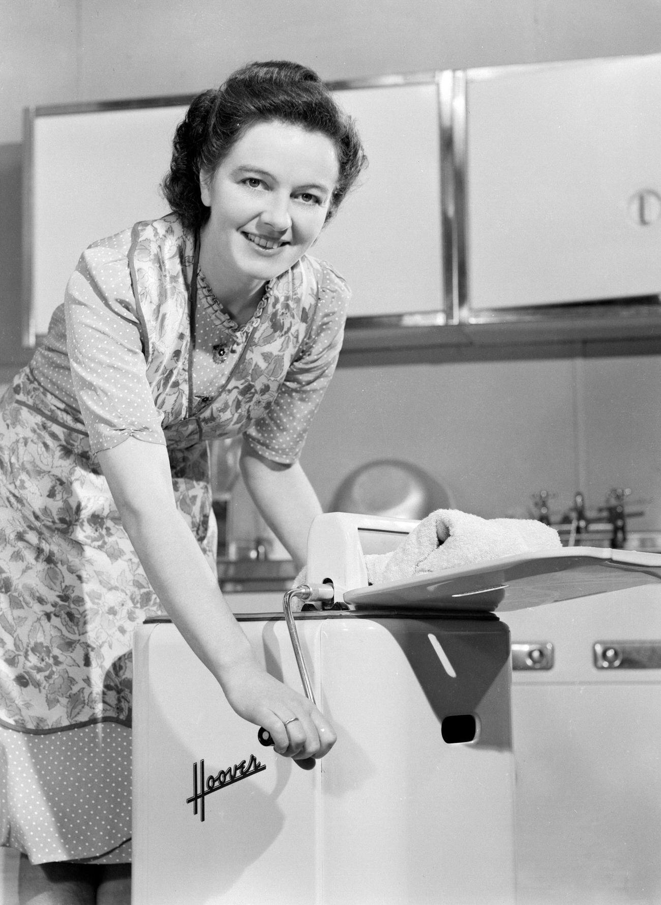 Woman operating a Hoover washing machine and wringer, UK, 1948.
