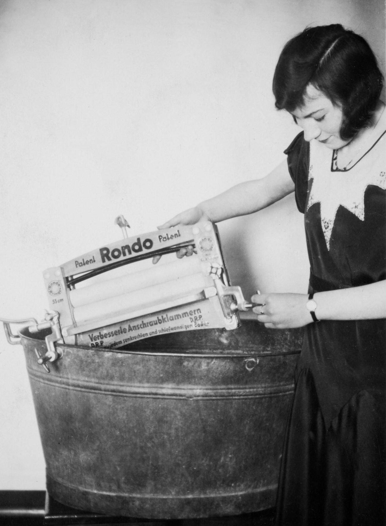 German woman installing a wringer over a wash tub, 1919.