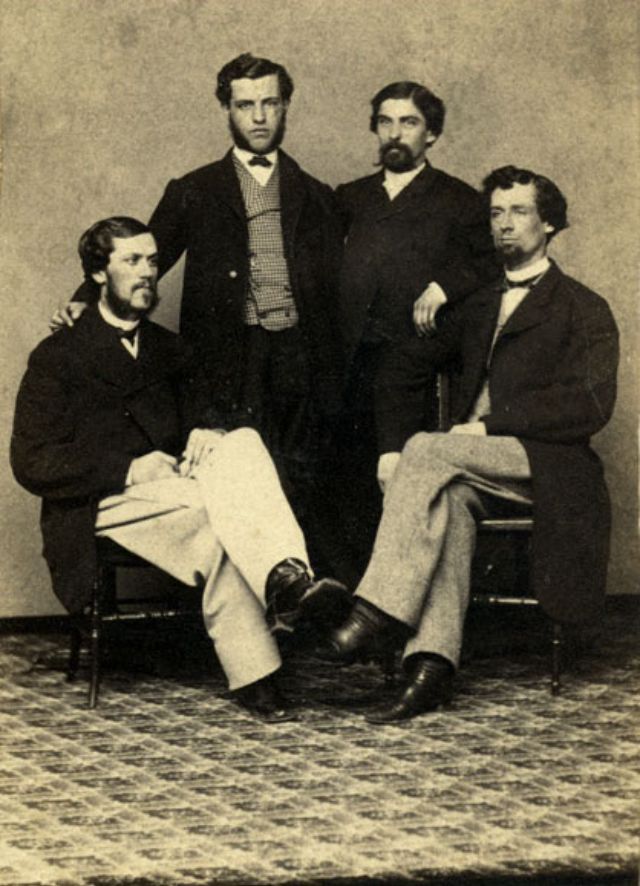 Four men pose before the camera operator