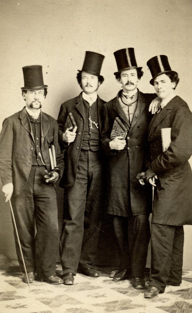 Gents in top hats with canes, gloves and books stand for their group portrait