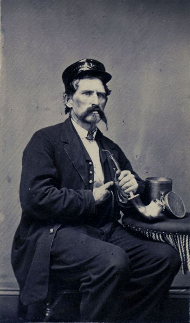 A gentleman poses with his pipe and a humidor