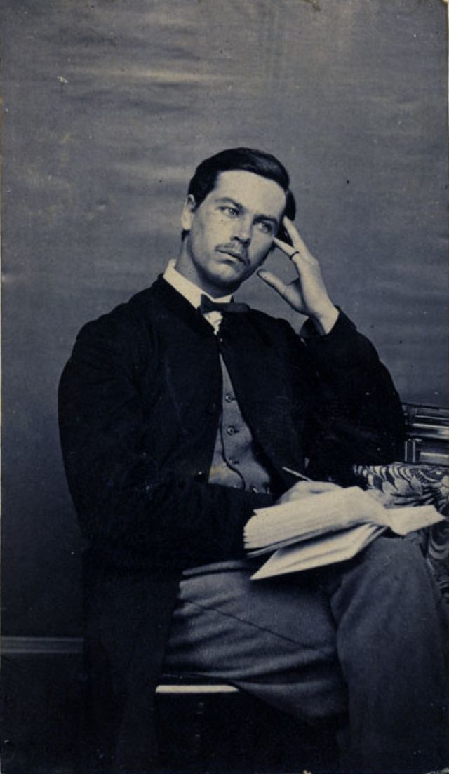 A man gazes away from the camera, forming his thoughts before putting pencil or pen to his journal