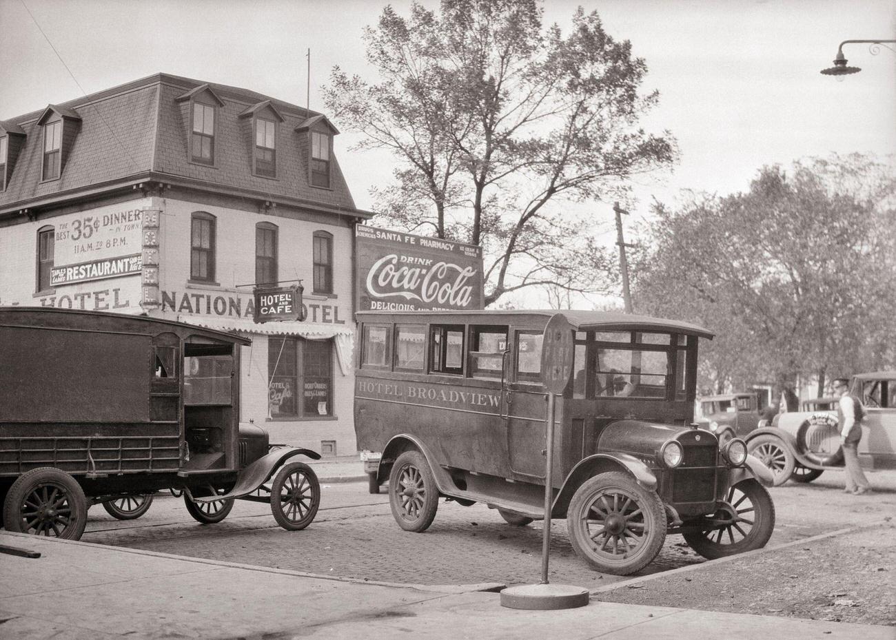 A 1920s motor bus and delivery van parked at a railway station in Emporia, Kansas, USA.