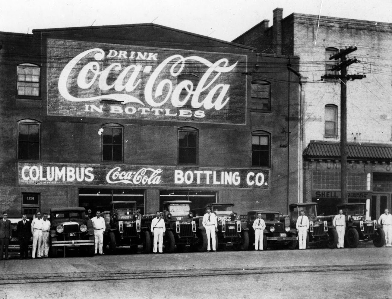 Coca-Cola delivery truck drivers beside their vehicles outside a bottling plant, 1921.