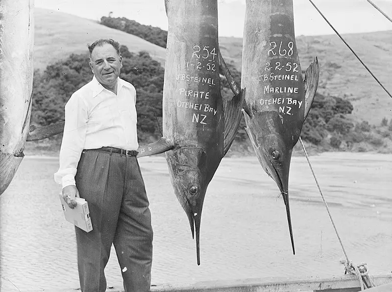 Man with two large suspended fish, 1952.