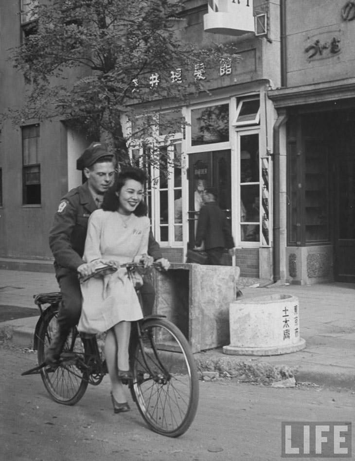 US soldier giving Japanese girl bicycle ride, Japan, 1946.