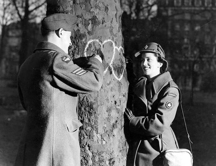 Young couple chalking hearts on tree, Valentine's Day, 1944.