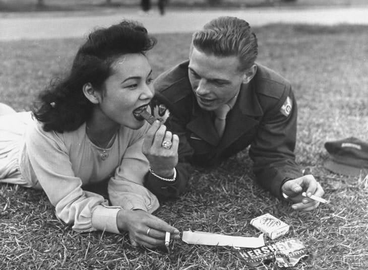US soldier sharing chocolate bar and cigarettes, 1940s.
