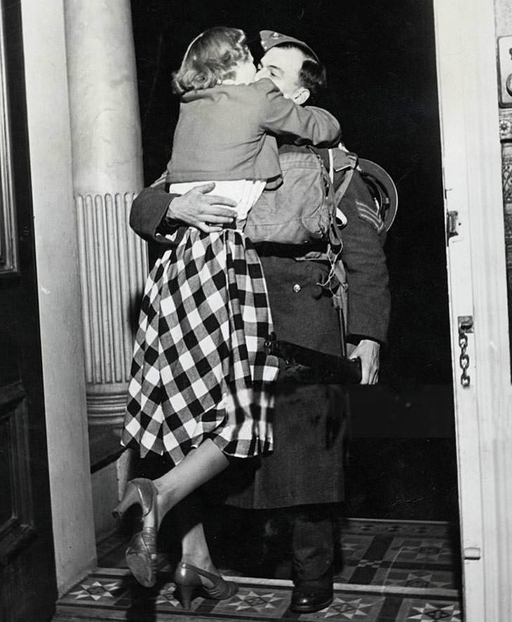 Soldier greeted with kiss from wife, home from France, Christmas.