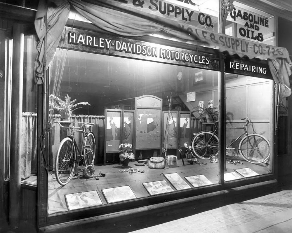 Mueller Cycle and Supply Co. window display with Harley-Davidson bicycles, fishing equipment, military images, and marketing materials, 1919.