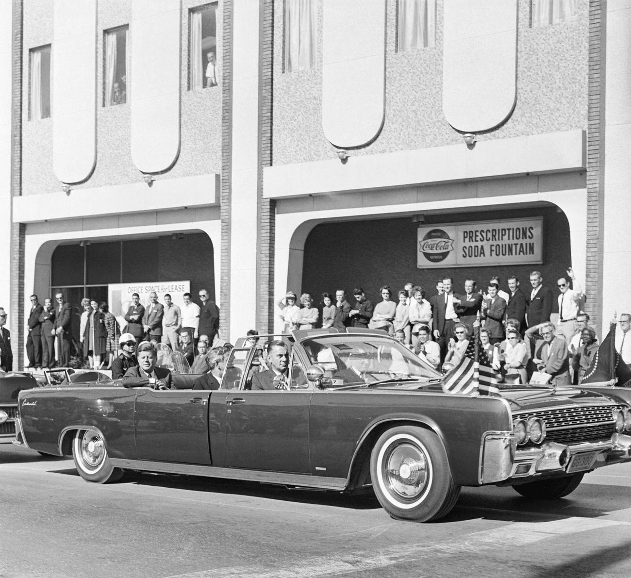 John F. Kennedy and Texas Governor John Connally ride in a convertible in Dallas, moments before the assassination, 1963.