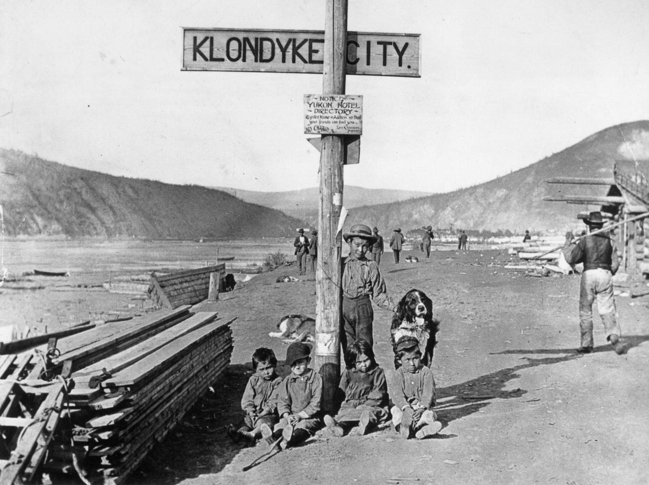 Children with their dog by a street sign in the Klondike area, Yukon Territory, Canada, 1890.