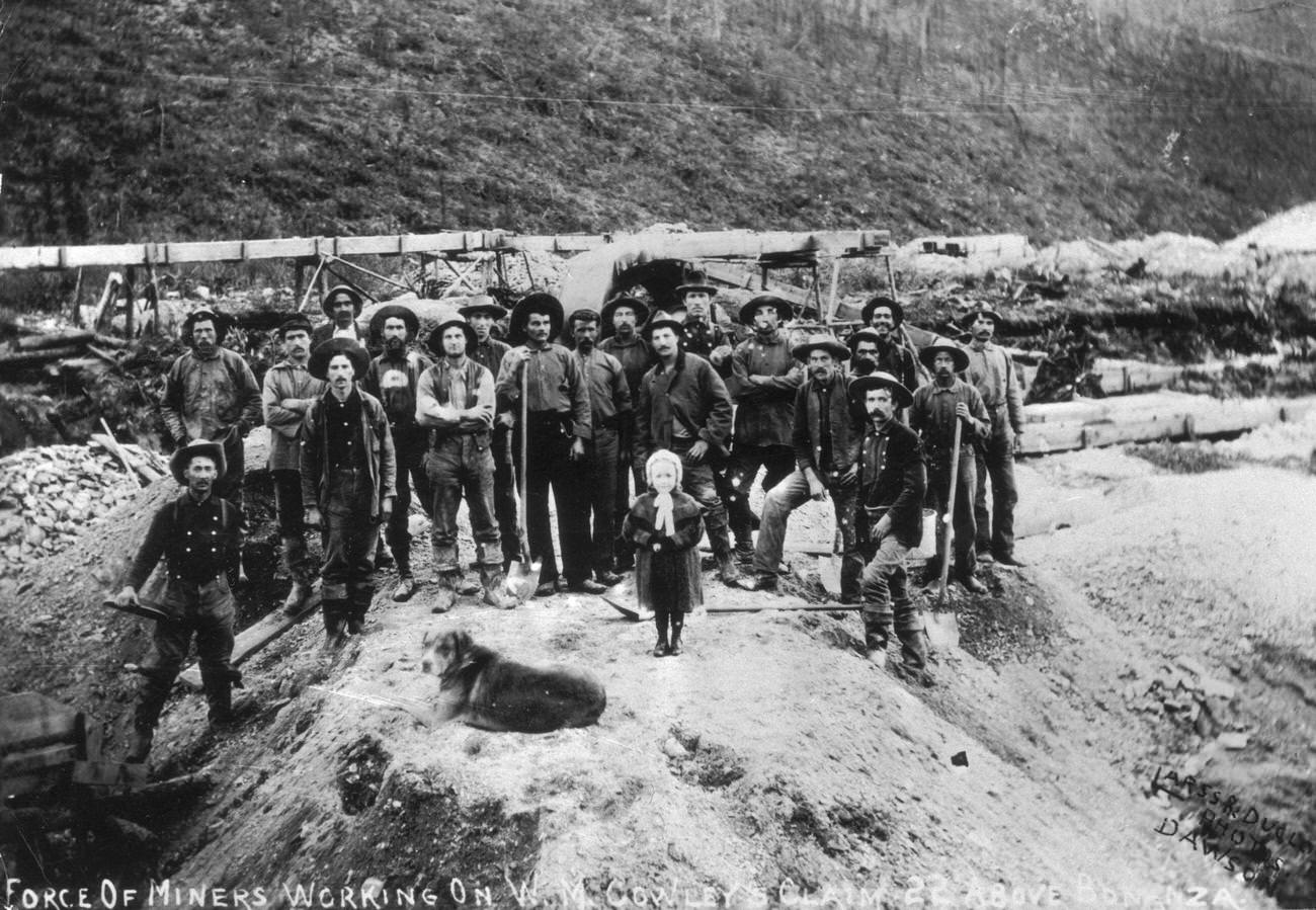 Portrait of gold miners working on W.M. Cowley's claim in Bonanza, Klondike, Alaska, with a dog, 1897.