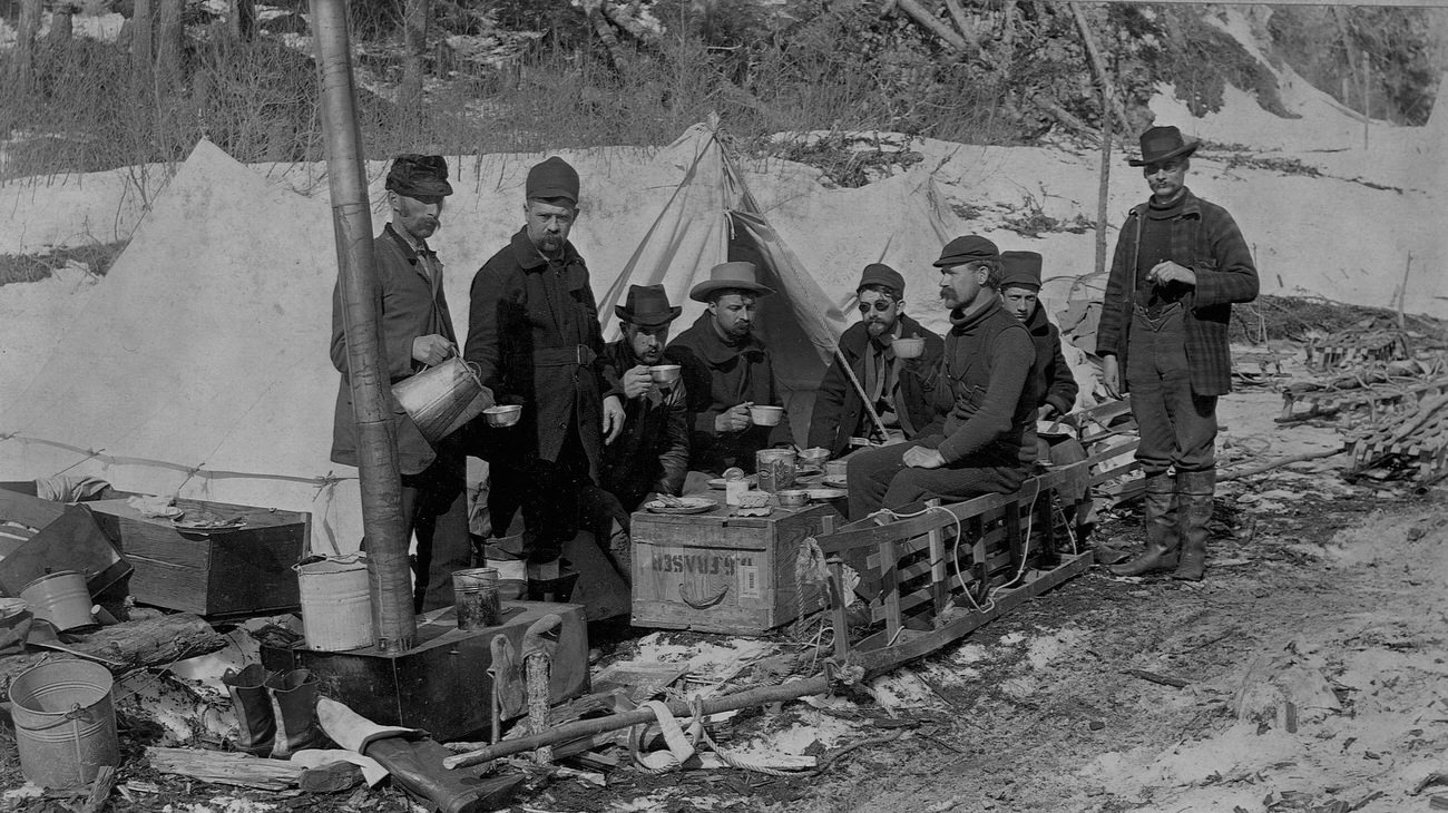 Prospectors lunching on a crate on the Yukon Trail, Alaska, 1897.