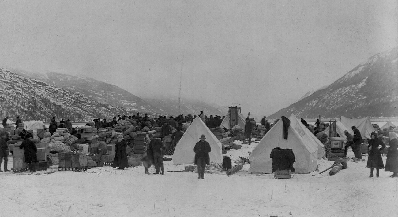 Prospectors and their gear on Dyea Flats, preparing for the Yukon gold fields journey, Alaska.