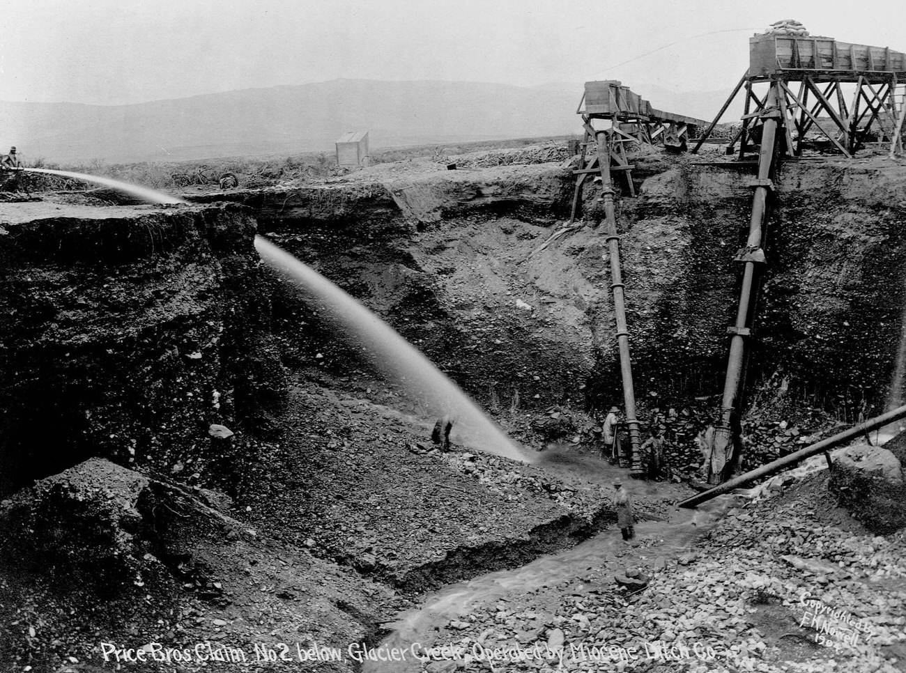Miners sluicing land near Glacier Creek, Alaska, for hydraulic gold mining.