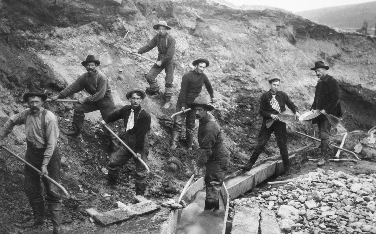 Miners pan and dig for gold in Alaska during the Klondike Gold Rush.