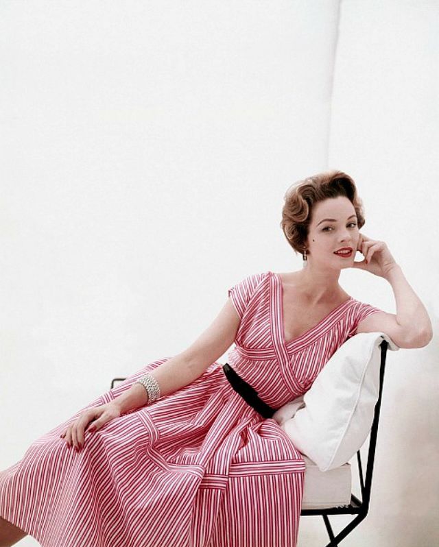 Linda Harper in a pink striped, V-back dress with a black patent leather belt by Henry Rosenfeld, 1953.