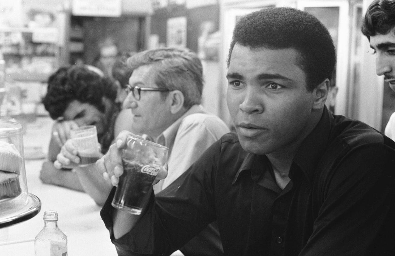 Boxer Muhammad Ali drinking Coca-Cola at a diner in Miami Beach, 1971.