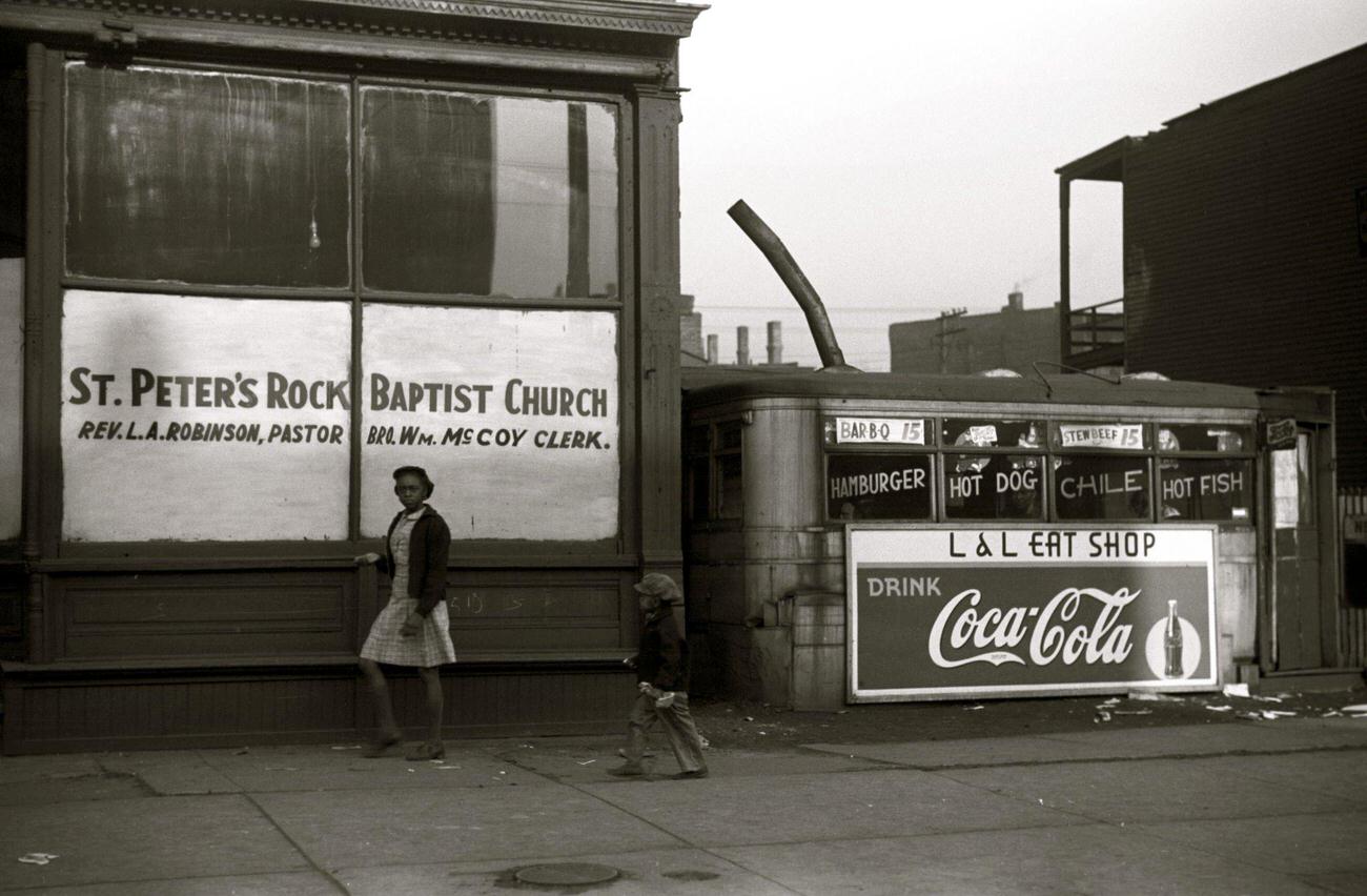 African American outside a storefront church and lunch wagon in the Black Belt, Chicago, Illinois, circa 1941.