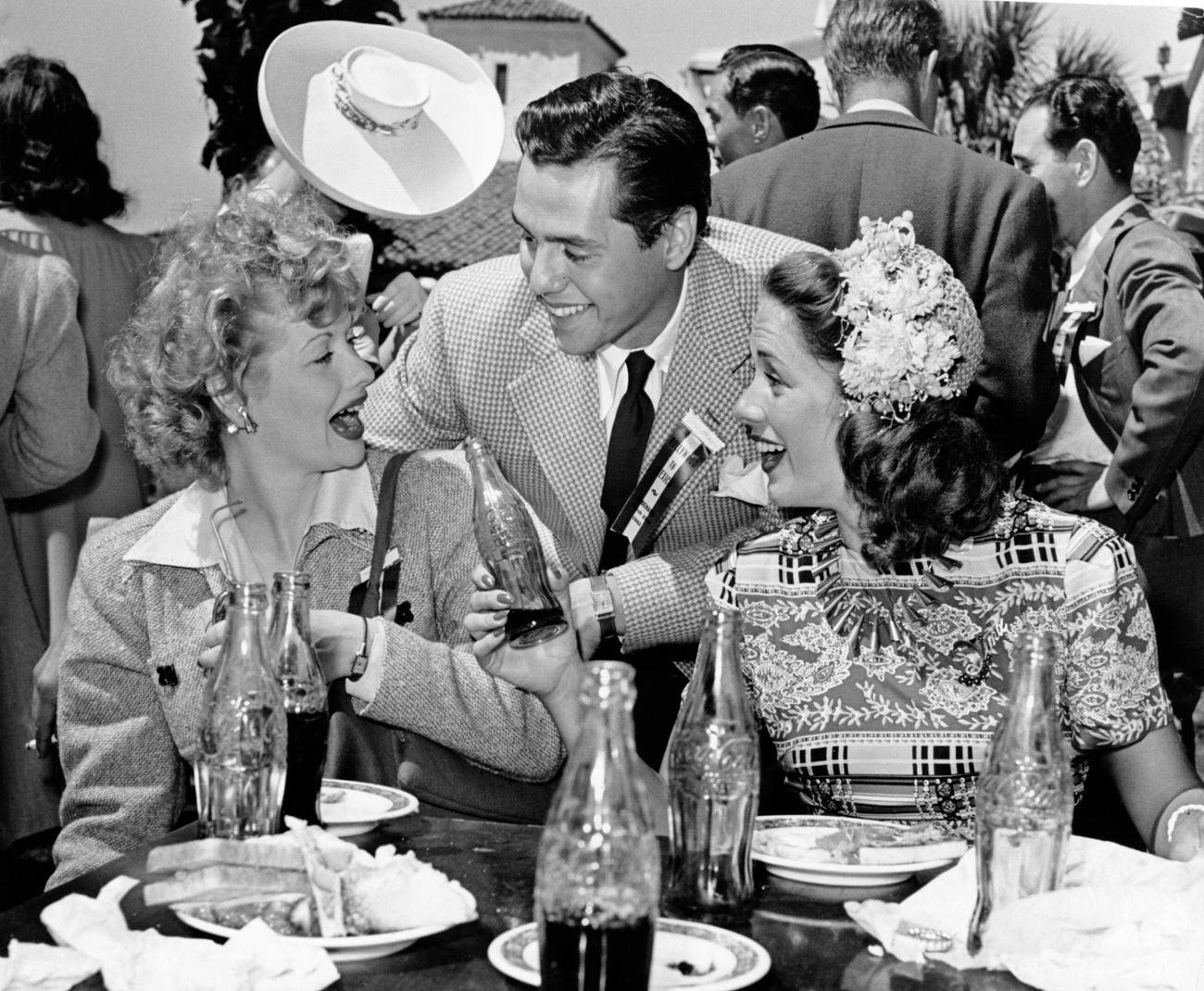 Married actors Lucille Ball and Desi Arnaz drinking Coca-Cola with actress Jinx Falkenburg, 1942.