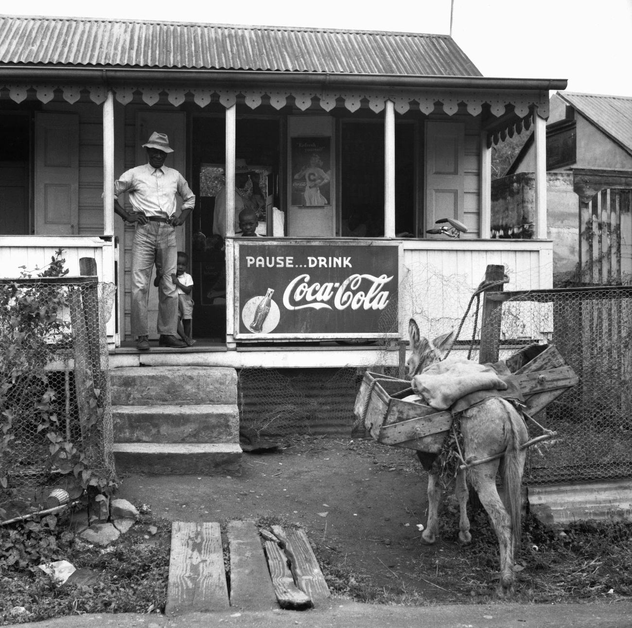 A merchant with his young son on the porch of his general store, date unspecified.