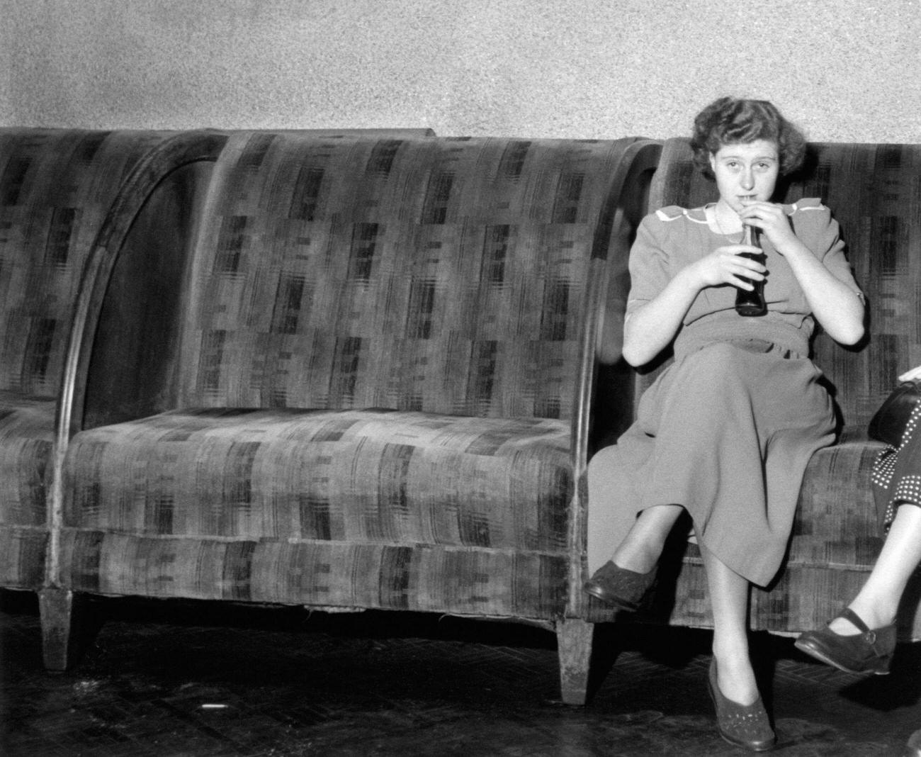 Woman sitting and drinking Coca-Cola in London, United Kingdom, 1950.