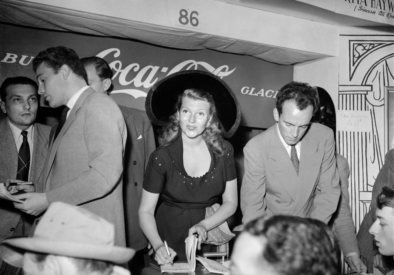 Actress Rita Hayworth signing autographs at a Coca-Cola stand in Paris, June 10, 1950.
