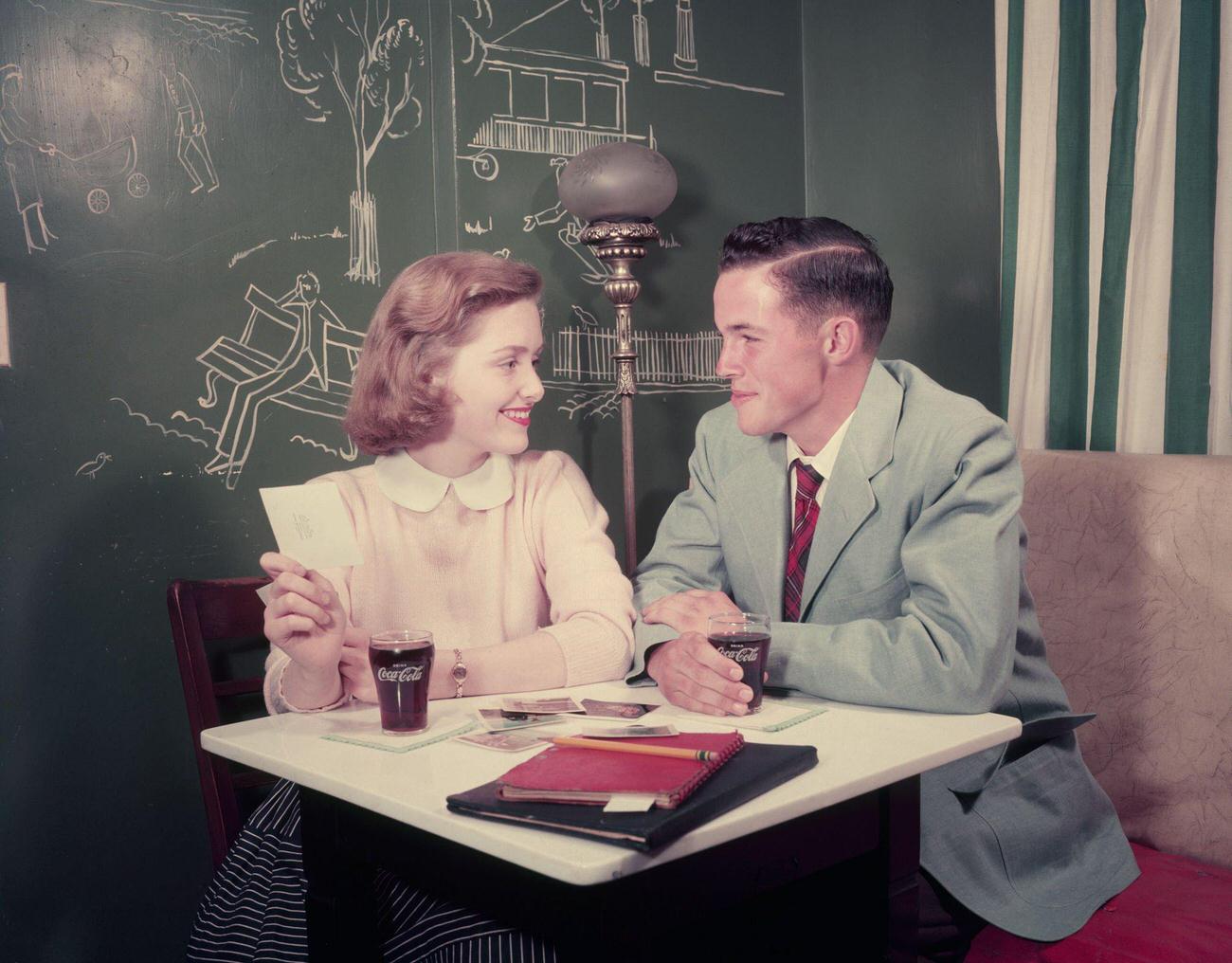 A couple sitting at a table having a Coca-Cola.